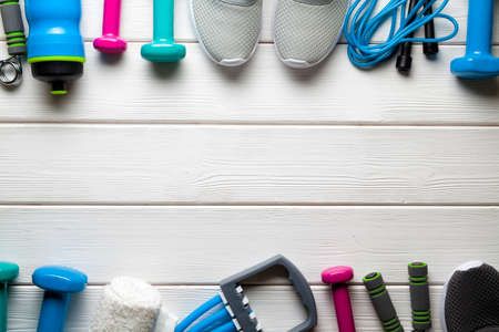 Fitness background - dumbbell, sneakers; bottle; jumping rope; towel and other equipment on wooden boardの写真素材