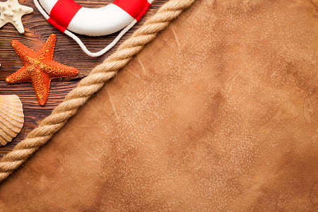 Marine background - shells, hawser, lifebuoy and blank paper sheet on wooden backgroundの写真素材