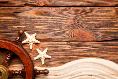 Starfish and ship's steering wheel on wooden backgroundの写真素材