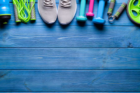 Fitness equipment on wooden background - bottle, dumbbell, jumping rope and sneakersの写真素材