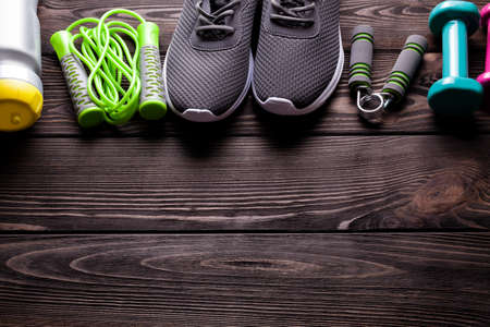 Fitness equipment - water, jumping rope, sneakers and dumbbell on wooden boardの写真素材