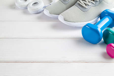 Fitness background - sneakers, dumbbell, earphones on white wooden boardの写真素材