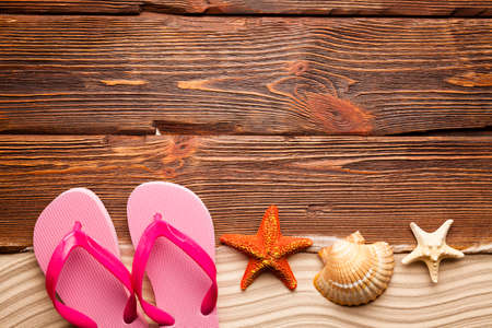 Shell, starfish, sand and flip flops on wooden boardの写真素材