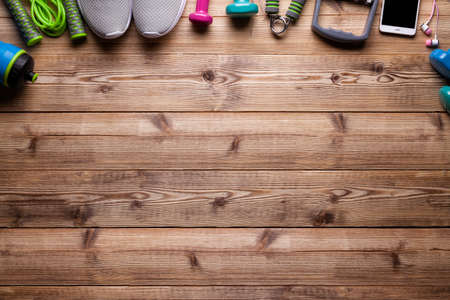 Fitness background - water, jumping rope, sneakers, dumbbell, smartphone, earphones on wooden boardの写真素材