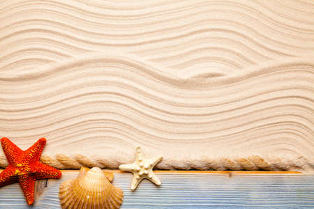 Starfish, shell and hawser on wooden plank and beach sandの写真素材