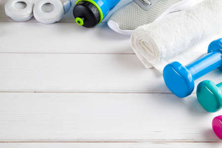 Sport and fitness symbols - sneakers, water, towel and dumbbell on wooden wall backgroundの写真素材