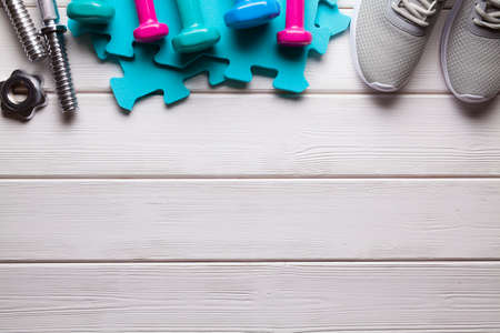 Sport symbols and accessories - dumbbell and sneakers on wooden backgroundの写真素材