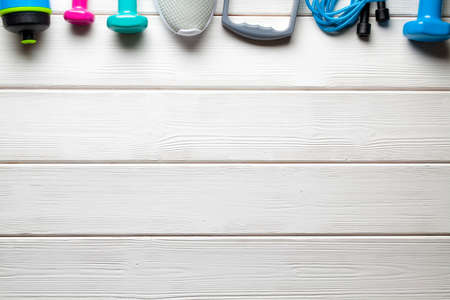 Sport background - fitness equipment; sneakers, jumping rope, dumbbell and water bottle on wooden...