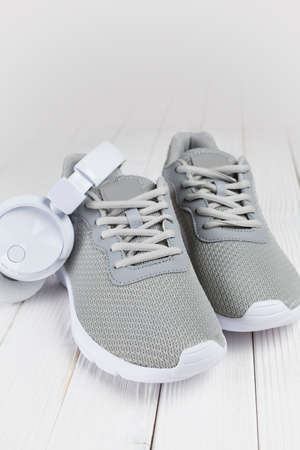 A pair of sports shoes and headphones on a wooden tableの写真素材