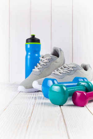 Sneakers, water and dumbbell on wooden wall background as a sport and fitness symbolsの写真素材