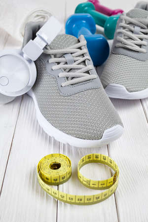 Sport and health symbols - shoes, earphones, dumbbell, towel and measure on wooden planksの写真素材