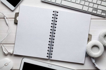 Opened notebook, tablet, smartphone, headphones and other computer accessories on white tableの写真素材