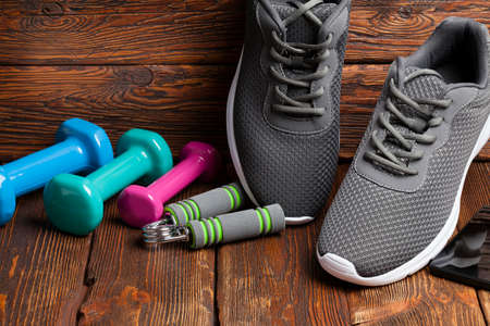 Sport accessories - colored dumbbells and sport shoes on wooden backgroundの写真素材