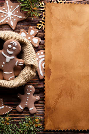 Gingerbread Christmas cookies and blank paper sheet on wooden backgroundの写真素材