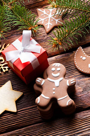 Christmas cookies, red gift box with white ribbon, branch of spruce tree on wooden backgroundの写真素材