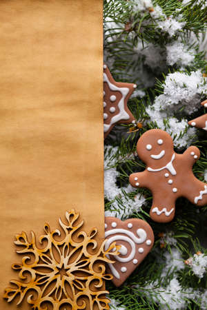 Blank paper sheet and Christmas gingerbread cookies on snow covered spruce branches