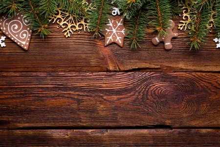 Branch of spruce tree, gingerbread cookies for Christmas and wooden decorations on wooden tableの写真素材
