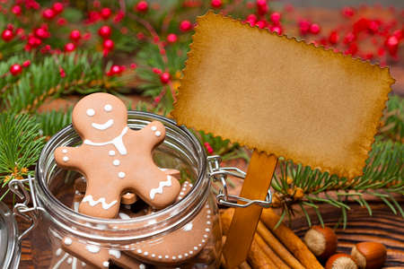 Gingerbread Christmas cookies in a jar and blank paper sheet on wooden tableの写真素材