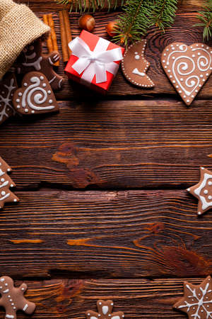 Christmas cookies, red gift box, cinnamon sticks and hazelnuts on wooden backgroundの写真素材