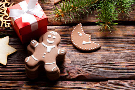 Gingerbread cookies, red gift box with white ribbon and spruce tree on wooden tableの写真素材