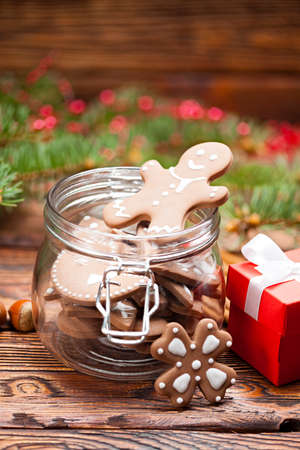 Gingerbread Christmas cookies in a jar, gift box and branch of spruce tree on wooden tableの写真素材