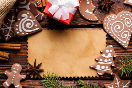 Christmas background - blank paper card, gingerbread cookies, spices and gift box on wooden tableの写真素材