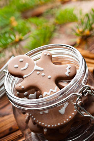 Gingerbread Christmas cookies in a jar and branch of spruce tree on wooden tableの写真素材