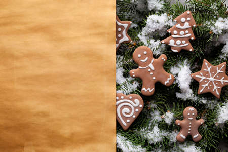 Blank paper sheet and Christmas gingerbread cookies on snow covered spruce branchesの写真素材