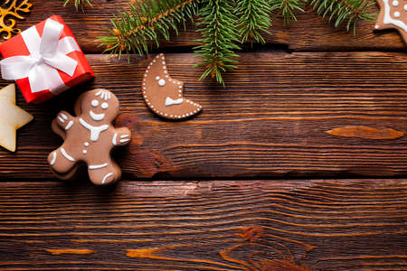 Christmas background - gingerbread cookies, red gift box and spruce tree on wooden backgroundの写真素材