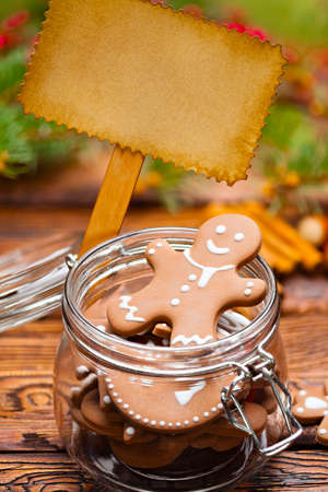 Gingerbread Christmas cookies in a jar and blank paper sheet on wooden tableの写真素材