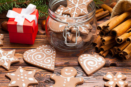 Gingerbread Christmas cookies in a jar, cinnamon sticks and gift box on wooden tableの写真素材