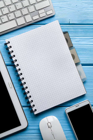 Notebook with copy space and modern electronics gadgets on blue wooden backgroundの写真素材