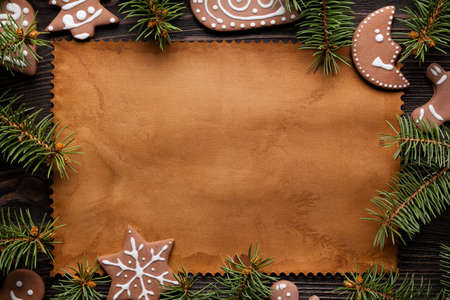 Christmas cookies, branch of spruce tree and handmade paper sheet on wooden tableの写真素材