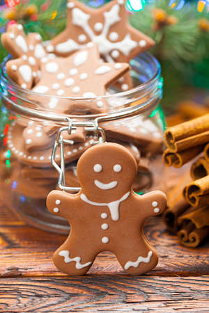 Gingerbread Christmas cookies in a jar and cinnamon sticks on wooden tableの写真素材