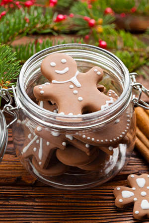 Gingerbread Christmas cookies in a jar, cinnamon, hazelnuts and branch of spruce tree on wooden tableの写真素材