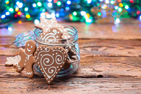 Gingerbread Christmas cookies in a jar and many colorful lights on wooden tableの写真素材