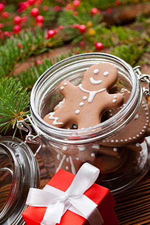 Gingerbread cookies in a jar, Christmas gift box and branch of spruce tree on wooden tableの写真素材