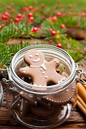 Gingerbread Christmas cookies in a jar, cinnamon, hazelnuts and branch of spruce tree on wooden tableの写真素材