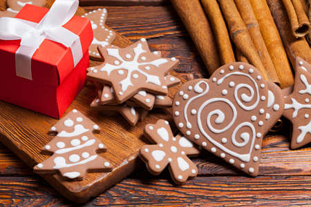 Red gift box and decorated gingerbread Christmas cookies on wooden tableの写真素材