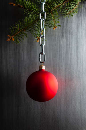 Red Christmas bauble on silver chain and spruce tree on steel metal backgroundの写真素材