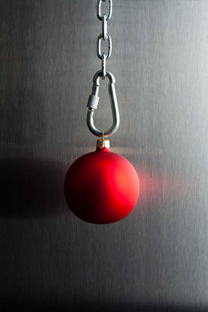 Red Christmas bauble on a chain and aluminum backgroundの写真素材