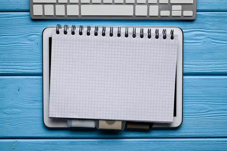 Notepad, digital tablet and computer keyboard on wooden tableの写真素材