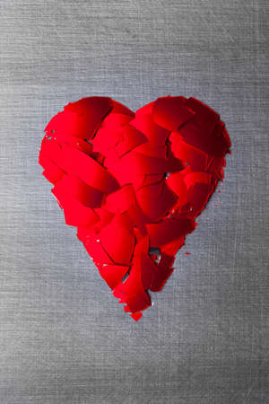 Heart shape from pieces of broken red glass on silver steel background
