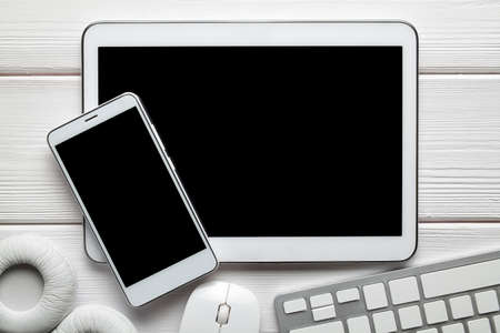 White modern smartphone and digital tablet, headphones, computer mouse and keyborad on white backgroundの写真素材