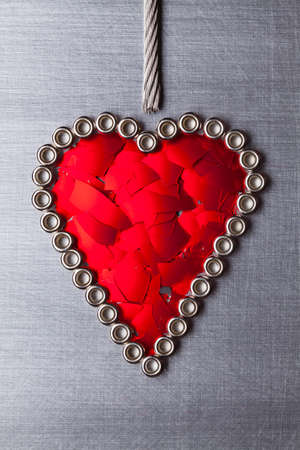Heart shape from pieces of broken red glass on silver steel backgroundの写真素材