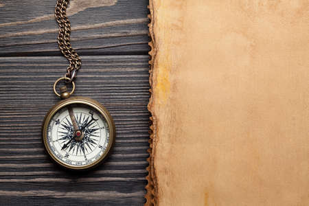 Vintage compass and blank paper sheet on wooden tableの写真素材