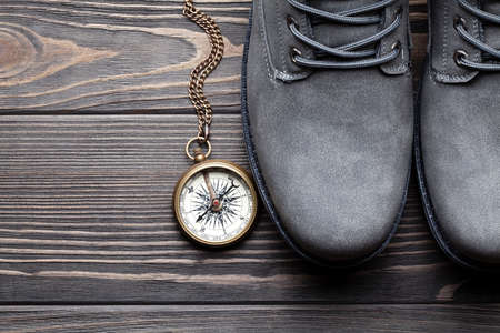 Pair of hiking boots and compass on wooden tableの写真素材