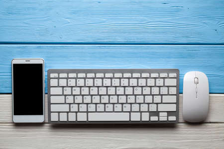 Smartphone, computer keyboard and mouse on wooden tableの写真素材