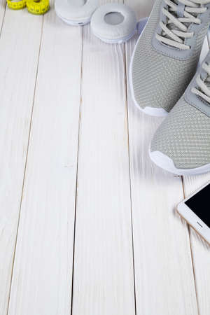 Smartphone, earphones, sport shoes, and measuring tape on wooden boardの写真素材