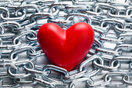 Red heart on steel chains backgroundの写真素材